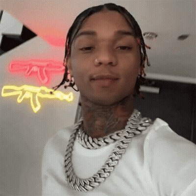 A Man Wearing A Chain Around His Neck Is Taking A Selfie In Front Of A Neon Sign . GIF