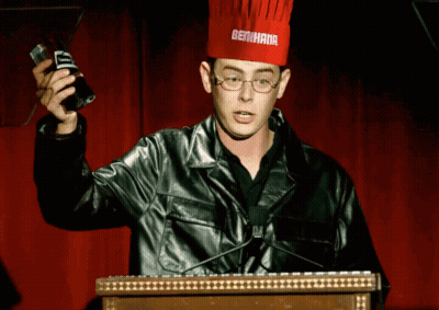 A Man Wearing A Chef 'S Hat With Bertha On It Stands At A Podium GIF