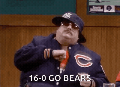 A Man Wearing A Chicago Bears Jacket Is Sitting At A Table In A Bar . GIF