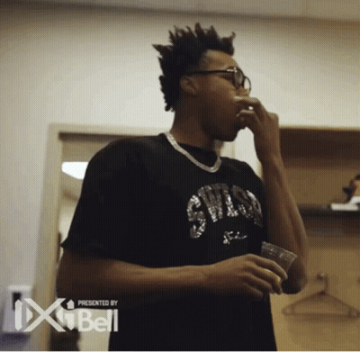 A Man Wearing A Chicago Bulls Shirt Is Drinking From A Cup GIF