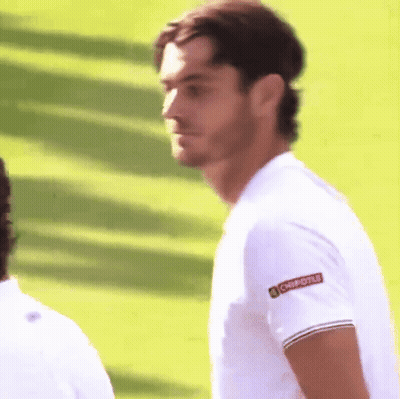 A Man Wearing A Chipotle Shirt Stands On A Lush Green Field GIF