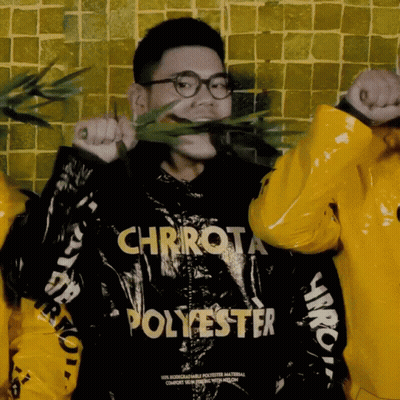 A Man Wearing A Chrrot Polyester Jacket Holds A Plant In His Mouth GIF
