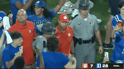 A Man Wearing A Clemson Hat Is Surrounded By Fans And Police Officers GIF