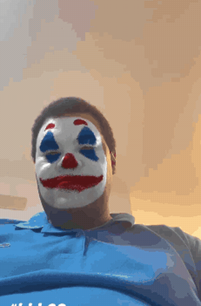 A Man Wearing A Clown Mask And A Blue Shirt GIF