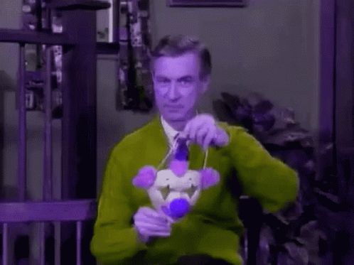 A Man Wearing A Clown Mask And Tie Is Holding A Microphone . GIF