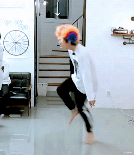 A Man Wearing A Clown Wig Is Dancing In A Room With A Sign That Says ' Lucky ' GIF