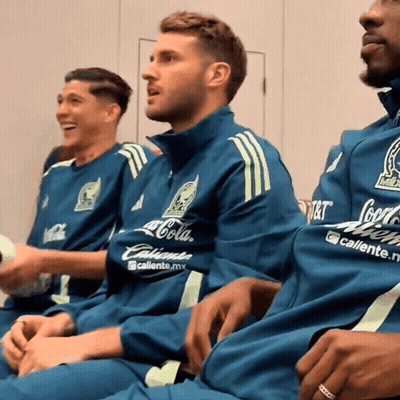 A Man Wearing A Coca Cola Shirt Sits With Two Other Men GIF