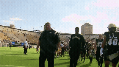A Man Wearing A Colorado Shirt Walks With A Group Of Football Players GIF