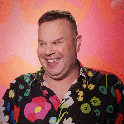 A Man Wearing A Colorful Floral Shirt Smiles For The Camera GIF