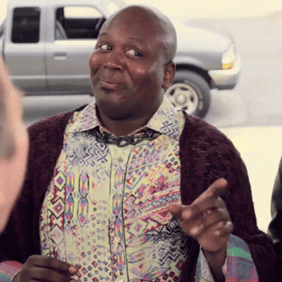 A Man Wearing A Colorful Shirt And A Purple Cardigan Is Talking GIF