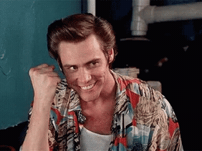 A Man Wearing A Colorful Shirt Is Smiling And Holding His Fist Up . GIF