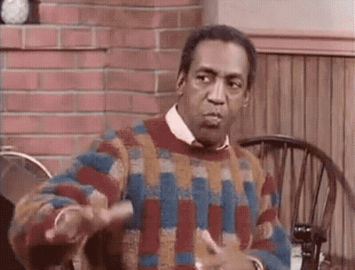 A Man Wearing A Colorful Sweater Is Sitting At A Table With A Chair . GIF