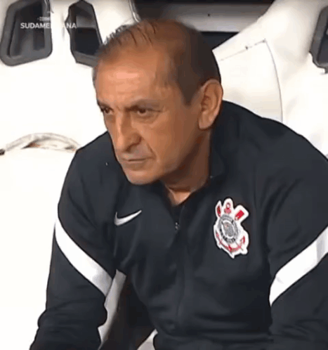 A Man Wearing A Corinthians Jersey Sits In A Chair GIF
