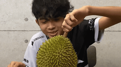 A Man Wearing A Corsair Shirt Is Eating A Durian GIF