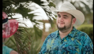 A Man Wearing A Cowboy Hat And A Blue Shirt Is Smiling GIF