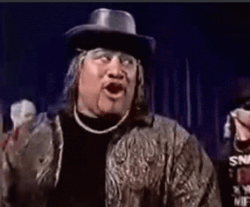 A Man Wearing A Cowboy Hat And A Jacket Is Making A Funny Face With His Mouth Open . GIF