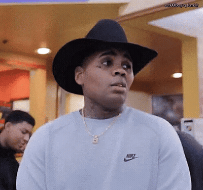 A Man Wearing A Cowboy Hat And A Nike Sweater Is Making A Funny Face . GIF