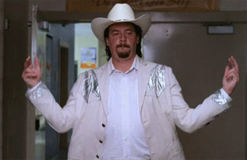 A Man Wearing A Cowboy Hat And A White Jacket Stands In A Hallway GIF