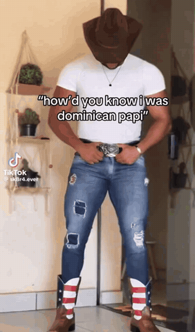 A Man Wearing A Cowboy Hat And Cowboy Boots Is Standing In Front Of A Wall . GIF