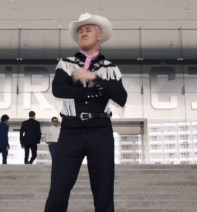 A Man Wearing A Cowboy Hat And Fringed Jacket Stands In Front Of A Building That Says Jrc GIF