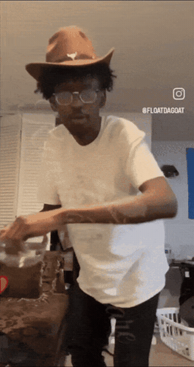 A Man Wearing A Cowboy Hat And Glasses Is Dancing In A Living Room GIF