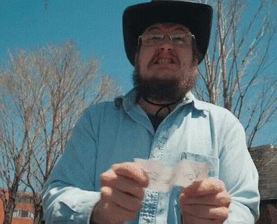 A Man Wearing A Cowboy Hat And Glasses Is Holding A Piece Of Paper That Says " I Voted " GIF