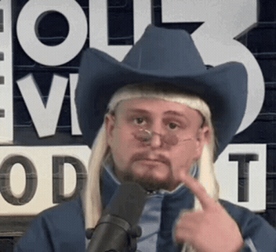 A Man Wearing A Cowboy Hat And Glasses Is Pointing To His Face . GIF
