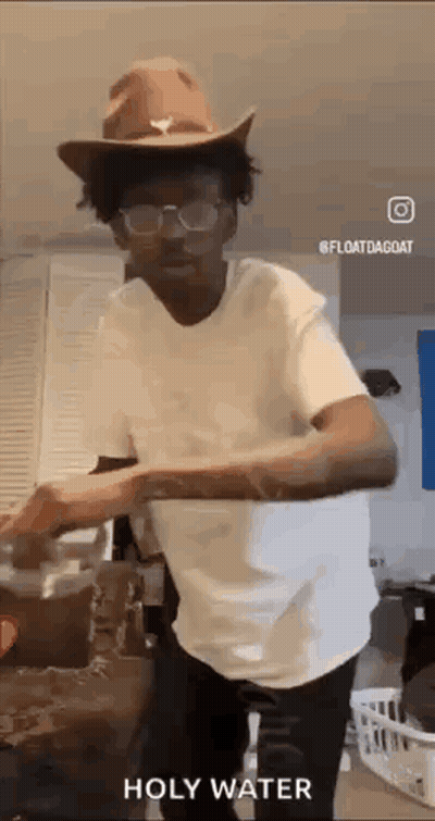 A Man Wearing A Cowboy Hat And Glasses Is Standing In A Kitchen . GIF