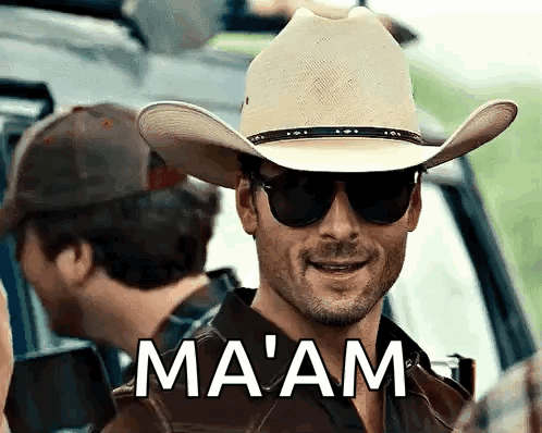 A Man Wearing A Cowboy Hat And Sunglasses Has The Word Ma 'Am On His Chest GIF