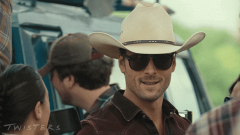 A Man Wearing A Cowboy Hat And Sunglasses Has The Word Twisters On The Bottom GIF