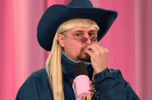 A Man Wearing A Cowboy Hat And Sunglasses Holds His Hand To His Nose GIF
