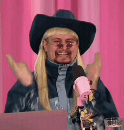 A Man Wearing A Cowboy Hat And Sunglasses Is Sitting In Front Of A Microphone . GIF
