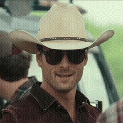 A Man Wearing A Cowboy Hat And Sunglasses Looks At The Camera GIF