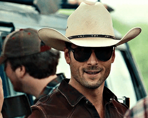A Man Wearing A Cowboy Hat And Sunglasses Looks At The Camera GIF