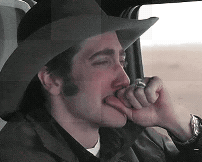A Man Wearing A Cowboy Hat Is Biting His Finger GIF