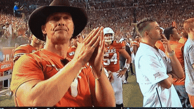 A Man Wearing A Cowboy Hat Is Clapping In Front Of A Player Wearing A Texas Jersey GIF