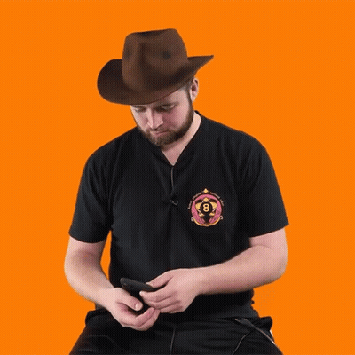 A Man Wearing A Cowboy Hat Is Looking At His Phone And The Word Whoa Is Below Him GIF