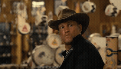 A Man Wearing A Cowboy Hat Is Looking At Something GIF