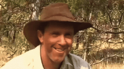 A Man Wearing A Cowboy Hat Is Smiling In Front Of Trees GIF