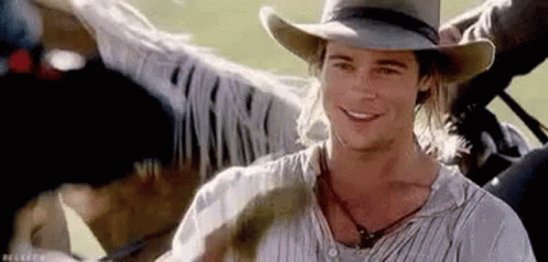 A Man Wearing A Cowboy Hat Is Smiling While Riding On The Back Of A Horse . GIF