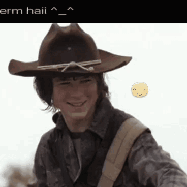 A Man Wearing A Cowboy Hat Is Smiling With A Yellow Smiley Face Behind Him GIF