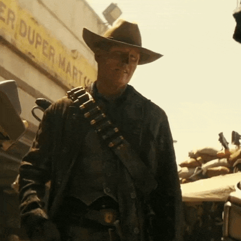 A Man Wearing A Cowboy Hat Is Standing In Front Of A Duper Mart GIF
