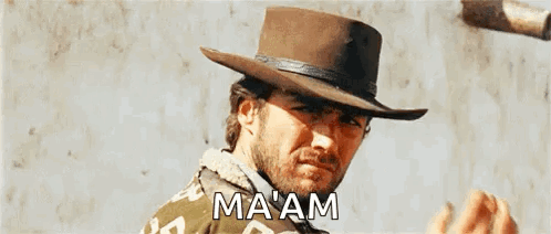 A Man Wearing A Cowboy Hat Is Standing In Front Of A Wall And Talking . GIF