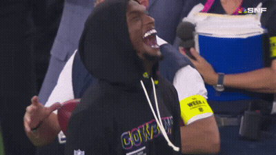 A Man Wearing A Cowboys Hoodie Laughs While Watching A Football Game GIF