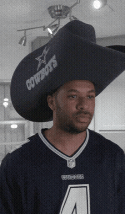A Man Wearing A Cowboys Jersey And A Large Hat GIF