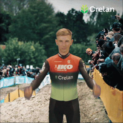 A Man Wearing A Crelan Jersey Is Standing In Front Of A Crowd GIF