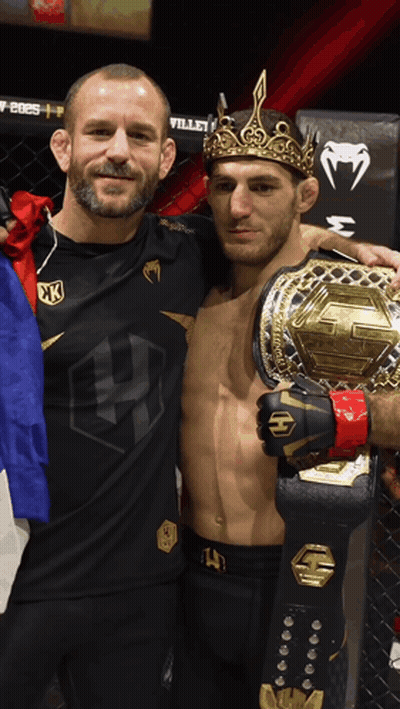A Man Wearing A Crown Is Holding A Championship Belt GIF
