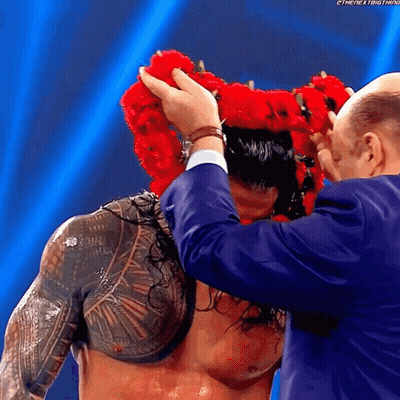 A Man Wearing A Crown Of Red Flowers On His Head GIF