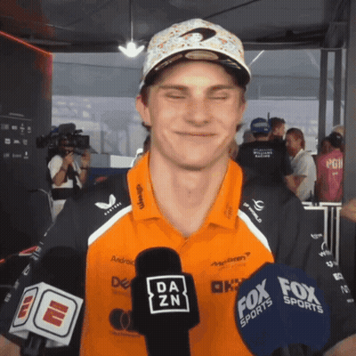 A Man Wearing A Da Zn Shirt Is Talking Into A Microphone GIF