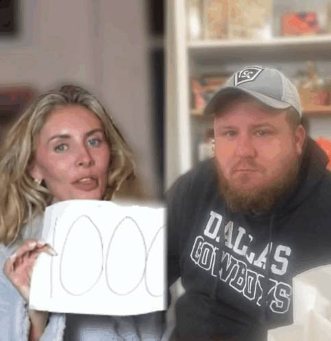 A Man Wearing A Dallas Cowboys Sweatshirt Holds Up A Sign GIF